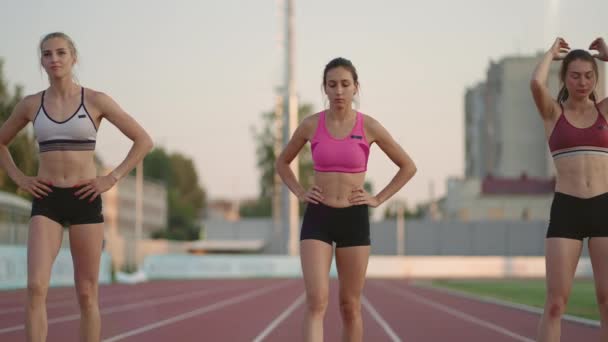 Un groupe de femmes à la compétition d'athlétisme se réchauffent et se préparent pour la course. Se concentrer sur la ligne de départ au stade — Video