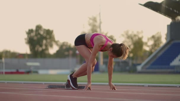 Jedna mladá žena běžec na slunci na stadionu aréně se připravuje na běh dostane do běžeckých bot a běží sprint z startovní čáry ve zpomaleném filmu — Stock video