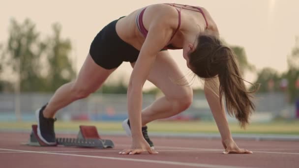 Caucasian young brunette woman shit for a run in the stadium comes up to the running sides and starts the sprint race in slow motion — Stockvideo