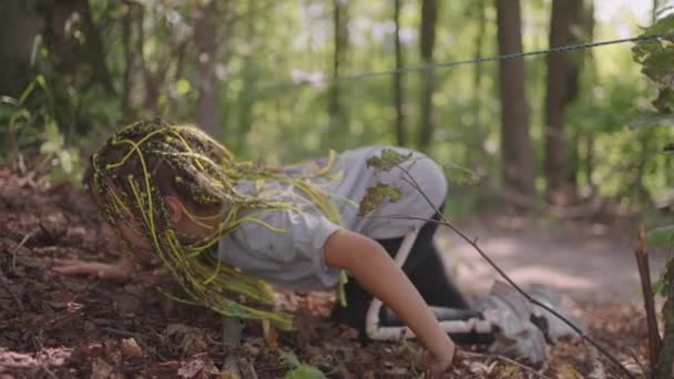 여름 캠프에서 하이킹을 하는 아이들은 땅을 기어갑니다. 땅 위를 기어 다녀서 장애물을 통과시키는 훈련. 한 소녀 가 수용소 임명을 받고 숲 속에 쓰러져 있다 — 비디오