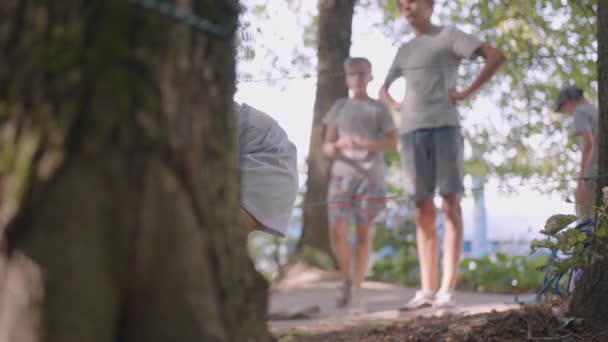 Crianças em um acampamento de verão caminhadas rasteja no chão. Treinamento de passar obstáculos rastejando no chão. Uma menina cai na floresta em uma missão de acampamento — Vídeo de Stock