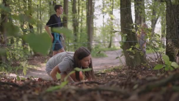 여름 캠프에서 하이킹을 하는 아이들은 땅을 기어갑니다. 땅 위를 기어 다녀서 장애물을 통과시키는 훈련. 한 소녀 가 수용소 임명을 받고 숲 속에 쓰러져 있다 — 비디오