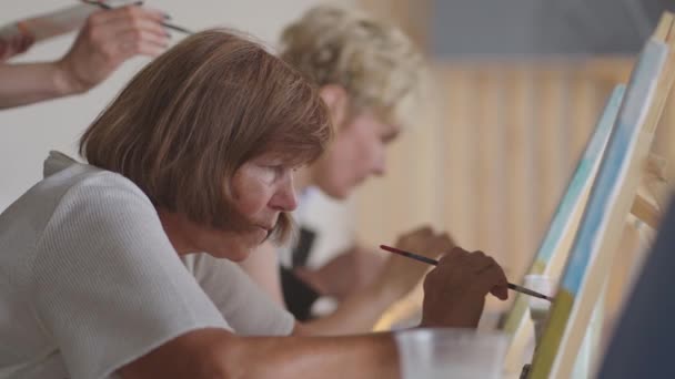 Een oude gepensioneerde vrouw schetst samen met vrienden een beeld. Een oudere groep vrienden en een oudere vrouw tekenen samen foto 's.. — Stockvideo