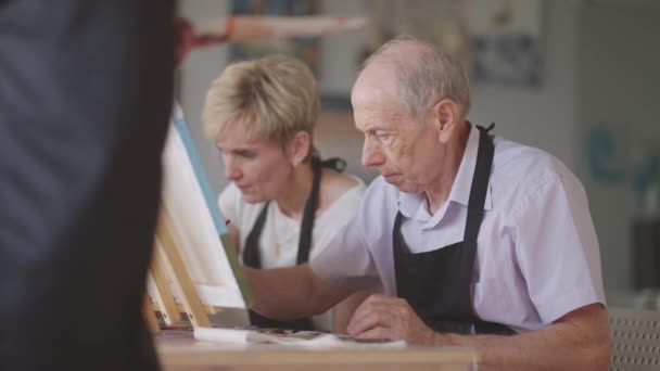 Senior man with friends draws a picture. The old mans club is having fun and painting together. — Stock Video