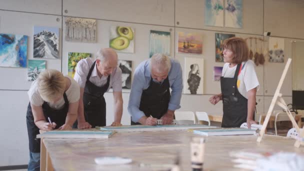 Щаслива група літніх людей малює фотографії разом у класі . — стокове відео