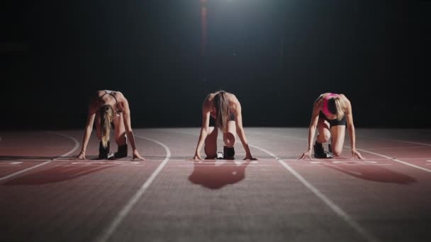 Front view zoom camera three women in the stadium at night in slow motion start and run to the camera — Stock Video