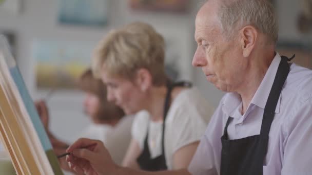 Senior man met vrienden tekent een tekening. De oude mannenclub heeft plezier en schildert samen.. — Stockvideo