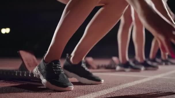 Cámara de primer plano sigue los pies de los corredores en zapatillas de deporte en la oscuridad con la luz de fondo que coincide con las zapatillas de correr — Vídeos de Stock