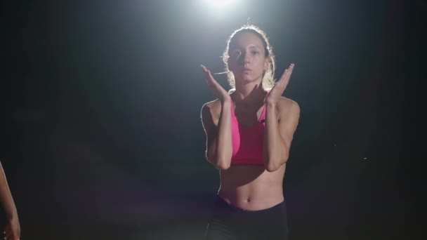 Tre kvinnliga löpare förbereder sig för att springa i ett mörkt ljus på arenan — Stockvideo