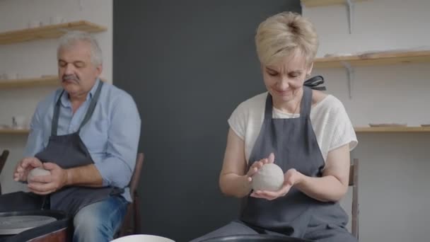 Skupina starších žen a muž se společně učí vyrábět keramiku na hrnčířském kole. Výroba nádobí na kole hrnčířů v důchodu — Stock video