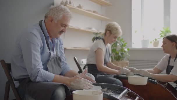 Genç bir kadın bir grup yaşlı kadına ve 60-70 yaşlarında bir adama çömlek yapmayı öğretiyor. Yaşlılar için etkinlikler — Stok video