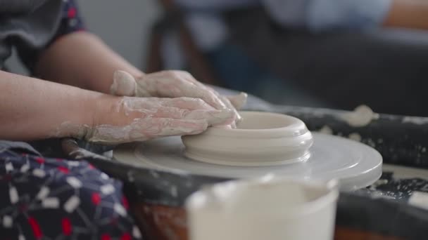 Närbild av handen på en grinig kvinna mästare arbetar på en keramik hjul i slow motion. Göra redskap med dina egna händer — Stockvideo