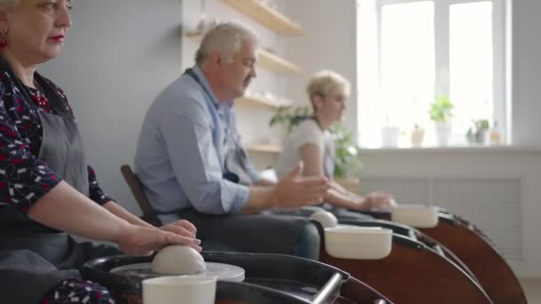 A group of senior women and a man together learn to make pottery on a potters wheel. Making utensils on a retired potters wheel — Stock Video