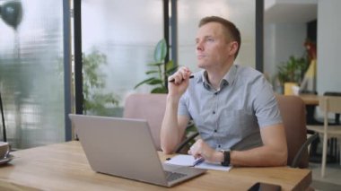 Genç düşünceli iş adamı problem çözümünü bilgisayarda çalışırken düşünüyor. Ciddi şüpheli erkek profesyonel dizüstü bilgisayara bakıyor piyasa risklerini düşünüyor, zor kararlar veriyor.