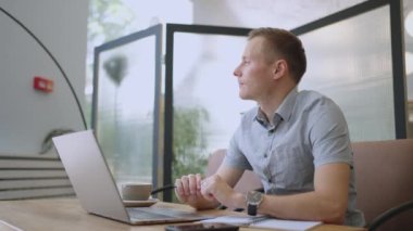 Genç düşünceli iş adamı problem çözümünü bilgisayarda çalışırken düşünüyor. Ciddi şüpheli erkek profesyonel dizüstü bilgisayara bakıyor piyasa risklerini düşünüyor, zor kararlar veriyor.