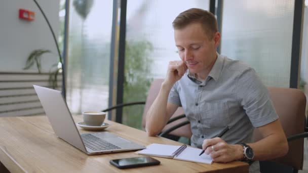 Pengembang laki-laki atau mahasiswa yang indah bekerja, belajar dengan laptop di kafe. freelance, pekerjaan jarak jauh, pendidikan online, bekerja sendiri — Stok Video