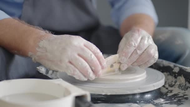 Close-up van de hand van een meester die aan een pottenbakkerswiel werkt voor de fabricage van klei en keramische kruiken en platen in slow motion — Stockvideo