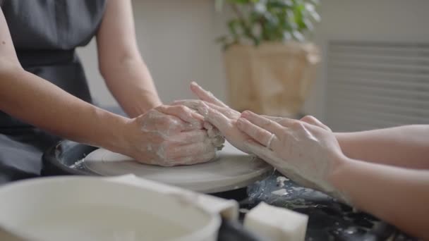 A female potters wheel sculpting teacher explains how to work and teaches an elderly woman to work with clay and make mugs and jugs. Master class for pensioners. Pottery courses — Stock Video