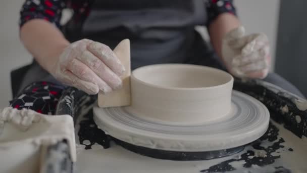 Close-up van de hand van een meester die aan een pottenbakkerswiel werkt voor de fabricage van klei en keramische kruiken en platen in slow motion — Stockvideo