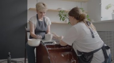 Kadın bir çömlekçi çarkları yontma öğretmeni, yaşlı bir kadına nasıl çalışacağını ve kille nasıl kupa ve sürahi yapılacağını öğretiyor. Emekliler için yüksek lisans sınıfı. Çömlek kursları