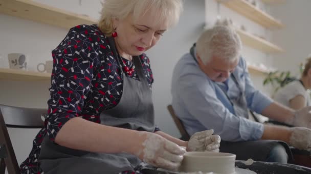Three elderly people work on a potters wheel in slow motion — Stock Video