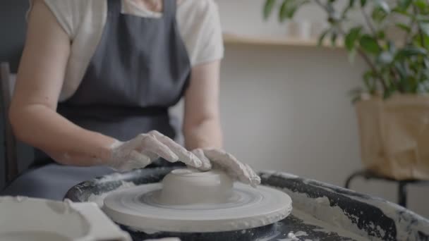 Mulher idosa mestre trabalha em uma roda de oleiros e faz uma caneca de cerâmica em sua oficina em câmera lenta — Vídeo de Stock