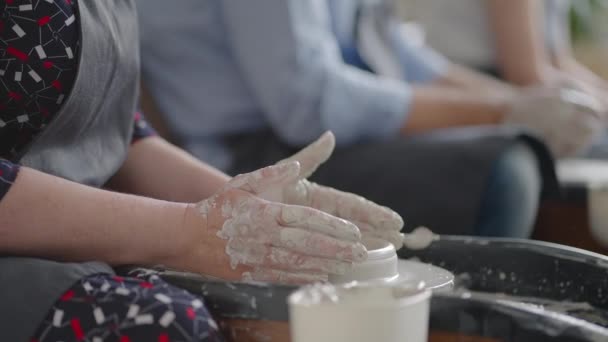 Close-up van de hand van een meester die aan een pottenbakkerswiel werkt voor de fabricage van klei en keramische kruiken en platen in slow motion — Stockvideo