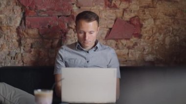 Güzel bir erkek müteahhit ya da öğrenci kafede dizüstü bilgisayarla çalışıyor. Serbest meslek, uzaktan eğitim, online eğitim, serbest meslek