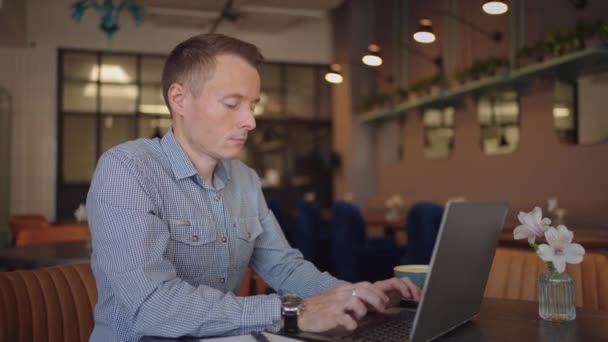 Schöne männliche Entwickler oder Studenten arbeiten, studieren per Laptop im Café. Freiberufler, Fernarbeit, Online-Bildung, Selbständige — Stockvideo