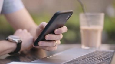 Cep telefonu olan bir adam internet bankacılığı yapıyor, internetten alıyor ve bir dizüstü bilgisayarla otururken sosyal ağlara mesajlar yazıyor.