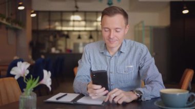 Cep telefonu olan bir adam internet bankacılığı yapıyor, internetten alıyor ve bir dizüstü bilgisayarla otururken sosyal ağlara mesajlar yazıyor.