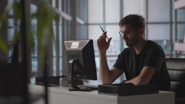 Um homem sério senta-se num computador no escritório e pensa. Analisa resolve um problema de crise. Uma fase difícil no negócio. Empresário atencioso — Vídeo de Stock