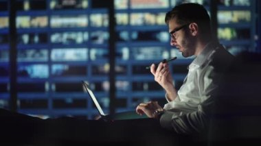 Genç adam hoparlörden ses tanıma mesajı kaydediyor. İş adamı sanal asistan uygulaması kullanıyor. Ev telefonunda akıllı bir hatırlatıcı kullanıyor. Dijital ai mobil yardım teknolojisi kavramı