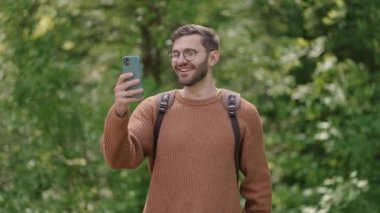 Ormanda yürürken sırt çantalı genç bir adam internetteki bir cep telefonuyla iletişim kuruyor ve yolculuktan bahsediyor. Videodaki turist, müdahaleciye manzarayı gösteriyor..