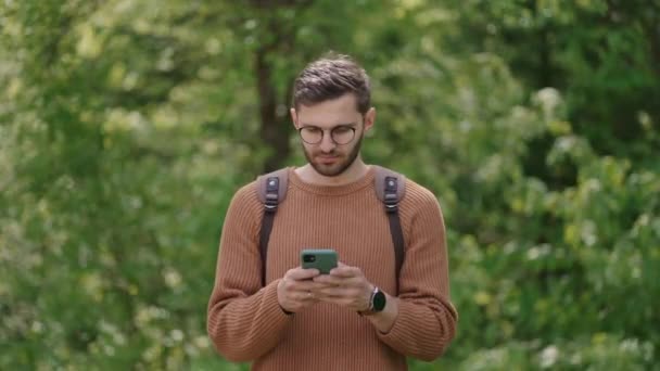 Ormanda cep telefonunda sırt çantalı bir adam internetten bilgi arıyor, haberleri okuyor, rezervasyon yapıyor. Doğadaki bir turist içeriği görür, GPS ile konum arar. — Stok video