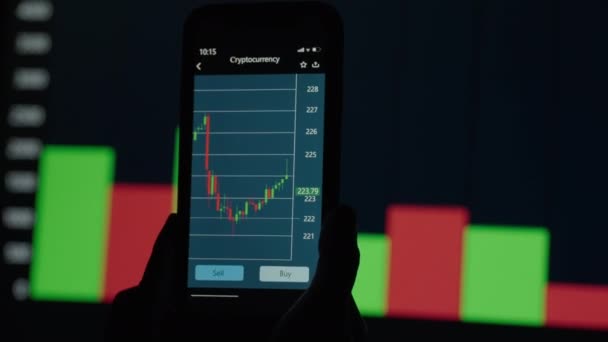 Mãos com um telefone móvel, verificando os dados do mercado de ações. Bolsa de Valores de Celular. Gráficos e tabelas em segundo plano — Vídeo de Stock