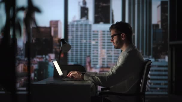 Toewijding is wat de beste resultaten oplevert. Zakenman op kantoor werkt aan een bureau op een laptop. man student schrijver zitten aan kantoor bureau met laptop denken van inspiratie zoeken probleem oplossing ideeën — Stockvideo