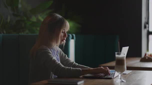 Jonge Aziatische aantrekkelijke vrouwelijke kantoormedewerker zittend aan een coffeeshop aan de laptop computer aan het bureau, werken en denken. — Stockvideo