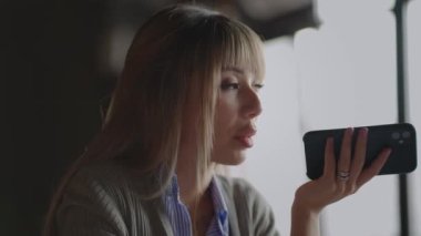 Mutlu Milenyum kızları cep telefonundan sanal asistanı aktifleştiriyor. Gülümseyen genç melez kadın arkadaş için sosyal ağda sesli mesajla cevap veriyor veya çevirmen kullanıyor.