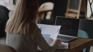 Asyalı İş kadını bir borsa grafiğini analiz ediyor. Genç bir Çinli, Japon, Japon, Koreli kadının kafasının arkasında dizüstü bilgisayarın büyük ekranından hisse senedi diyagramına bakıyor.