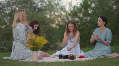 Açık havada genç kadınlar kil modellik kursuna gidiyor. Bir bayan işlemin fotoğraflarını telefonla çekiyor, akıllı telefonla, fotoğraf çekiyor. İletişim, hobiler, kadın çemberi, yaratıcı aktivite.