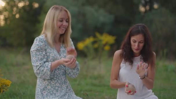 Un grupo de mujeres jóvenes esculpe de arcilla en la naturaleza, en un parque, en un espacio abierto. Dos chicas se dedican a modelar de cerca, sonreír, hablar, disfrutar del proceso. — Vídeos de Stock