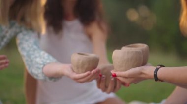 Genç kızlar doğada, parkta, açık alanda kilden modellik yapıyorlar. Grup kreatif dersleri, kil modelleme eğitimi. Kadınların elleri kilden ürünleri yakın planda tutar..