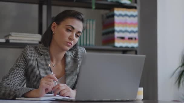 Arabische hispanische Frau, die Finanzpapiere bearbeitet, sitzt am Arbeitsplatz mit Laptop und sieht konzentriert aus, während sie Aufgaben stellt, vorbereitet, Berichte überprüft, die einen fruchtbaren Arbeitstag haben. Lernprozesskonzept für Schüler — Stockvideo