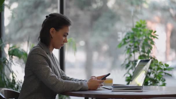 Indische, hispanische Frau verbringen ihre Freizeit mit der Nutzung des sozialen Netzwerks im Internet und lesen Multimedia-Nachrichten. Business-Araberin chattet auf Handy und arbeitet mit Laptop in Wohnung. — Stockvideo