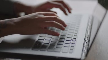 Evde oturan dizüstü bilgisayarın klavyesinde daktilo eden genç bir kadın. Evden uzak bir iş. İçişleri Bakanlığı