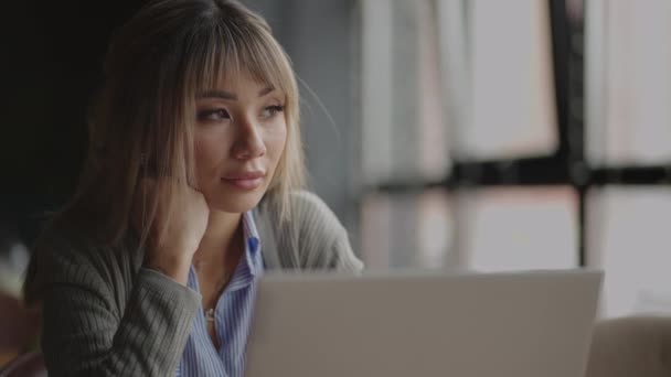 Uma jovem asiática sente falta de olhar para seu laptop. retrato de um estudante asiático cansado — Vídeo de Stock