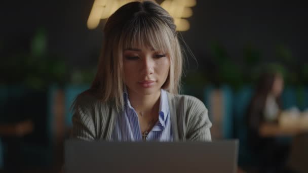 Asian student working at a laptop remotely in the campus library — Stock Video