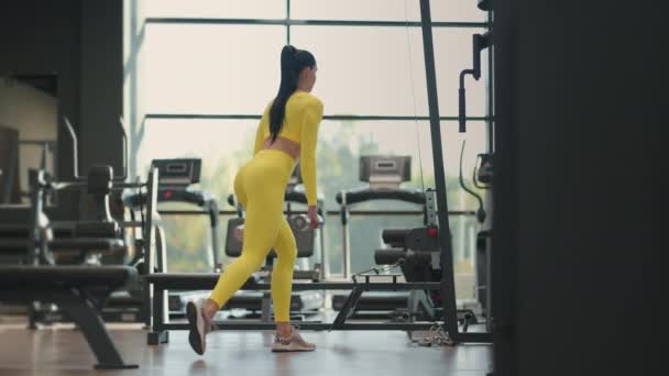 Mulher hispânica jovem musculoso fazendo exercício Lunges com halteres no ginásio em sportswear amarelo. Atleta feminina se exercitando com halteres em uma posição lunge no ginásio. — Vídeo de Stock