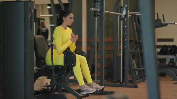 Sterke Spaanse atleet die beenverdunningsoefeningen doet op de simulator. brunette vrouw workout op been pers in sportschool in geel sportkleding — Stockvideo